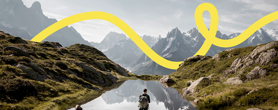 Man stands on rock in front of an alpine landscape with a lake (Photo)