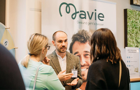 Man talks to two women in front of a mavie poster (Photo)