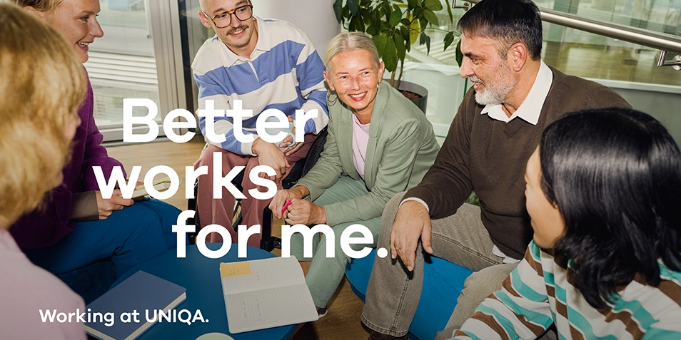 A group of people sitting and smiling in an office setting.

