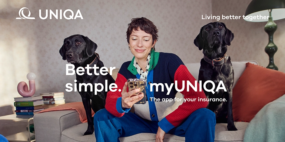 A woman sitting on a sofa with two dogs, holding a smartphone.
